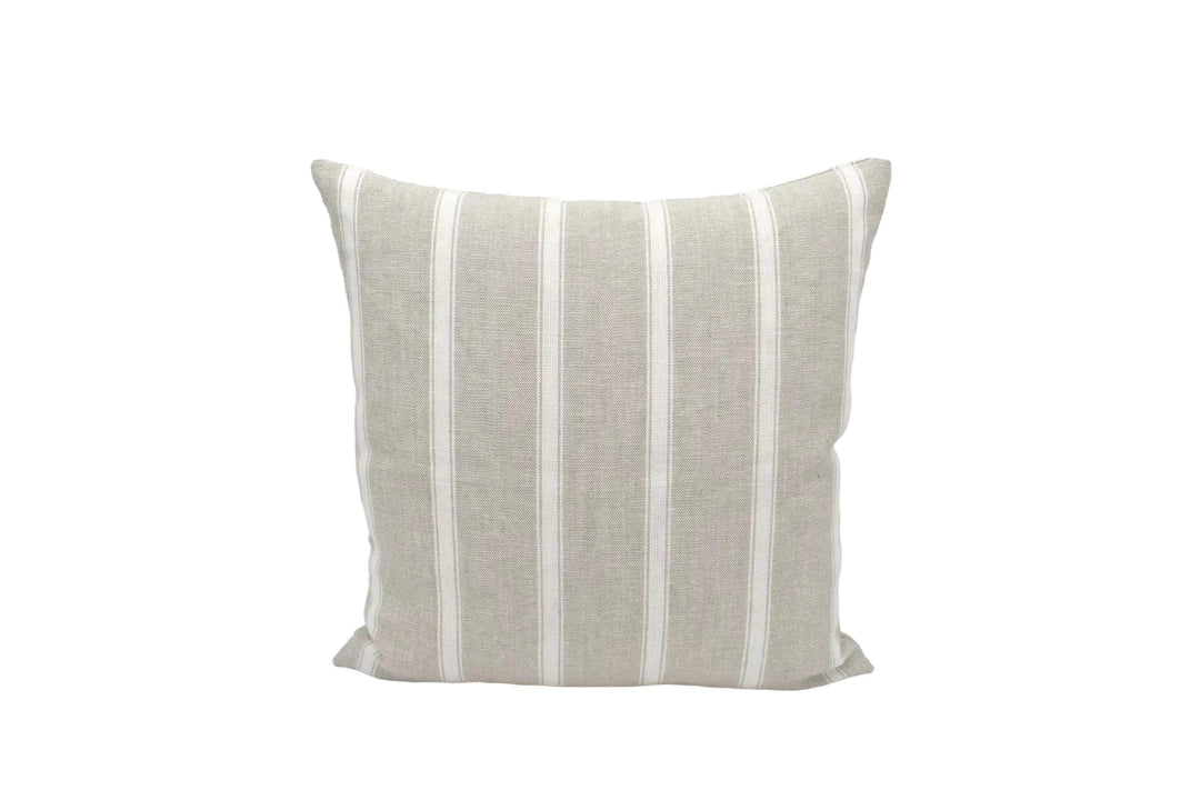 A beige and white striped pillow is placed against a white wall.