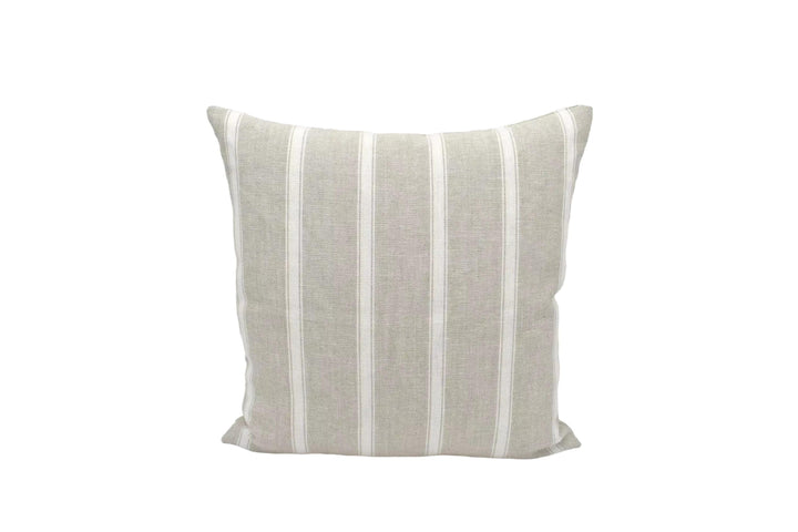 A beige and white striped pillow is placed against a white wall.