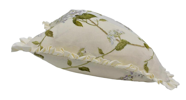 A white decorative pillow with a floral pattern and ruffled edges.
