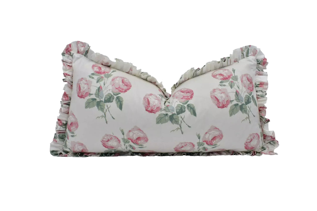 A white pillow with a floral pattern of pink roses and green leaves.