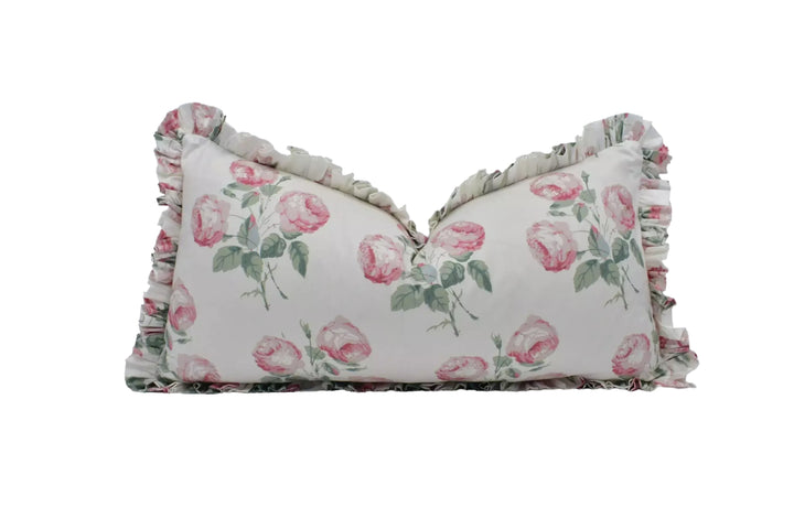 A white pillow with a floral pattern of pink roses and green leaves.