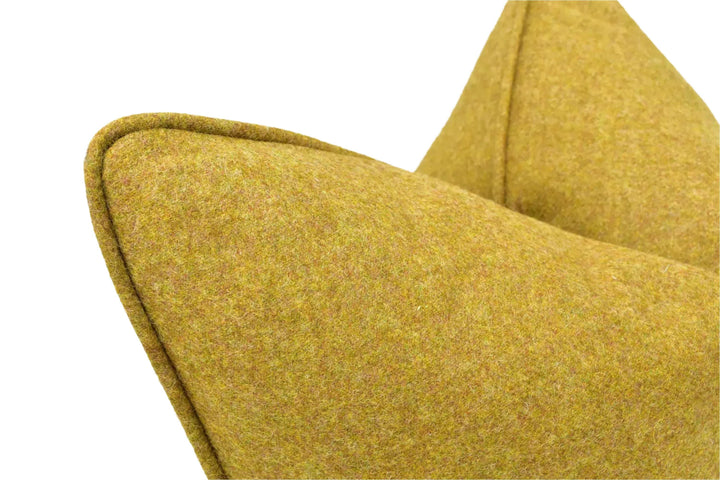 A close-up view of a yellow, textured fabric or material, possibly a pillow or cushion, with a pointed shape and a slight curve.