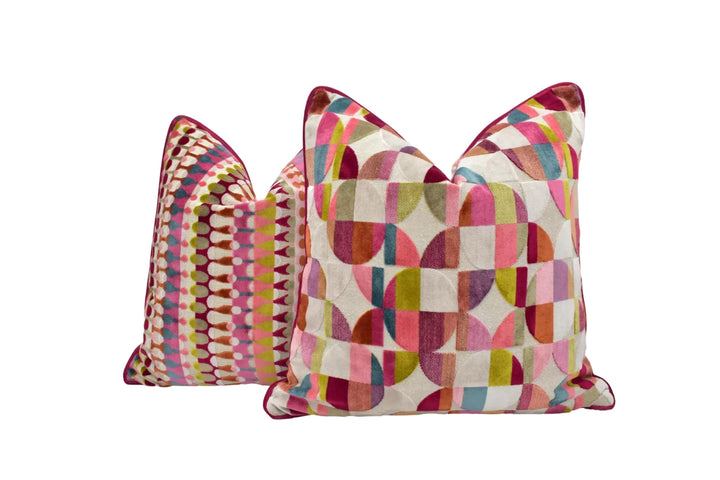 two colorful, patterned pillows with a geometric design in shades of pink, green, and yellow.