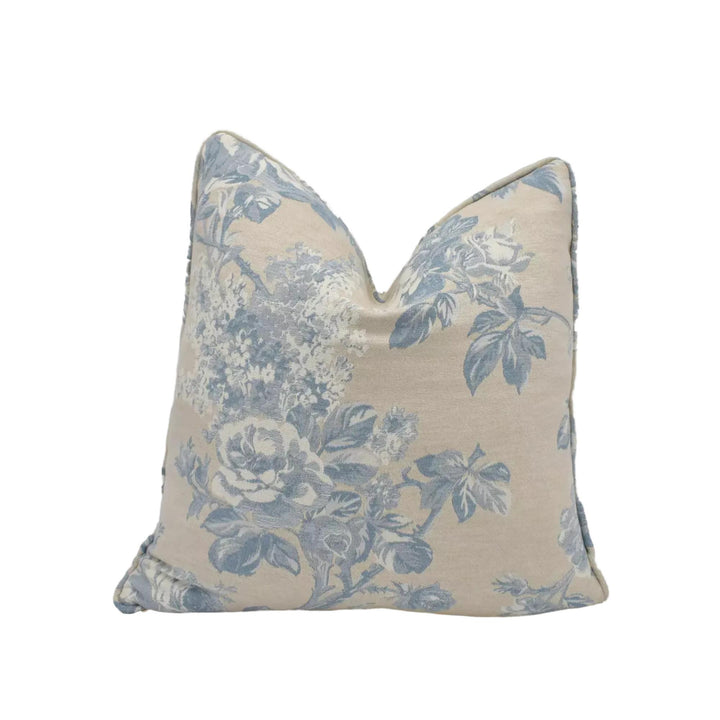A beige and blue floral patterned pillow against a white background.