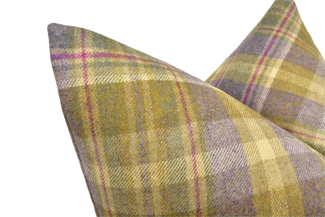 A close-up image of a decorative pillow with a plaid pattern in shades of green, yellow, and purple.